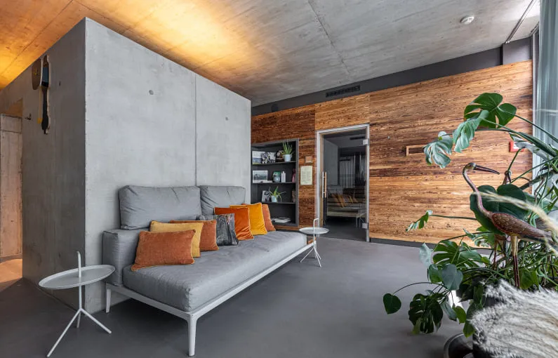 Gemütlicher Wohnraum mit grauem Sofa und einem Holzpaneelhintergrund