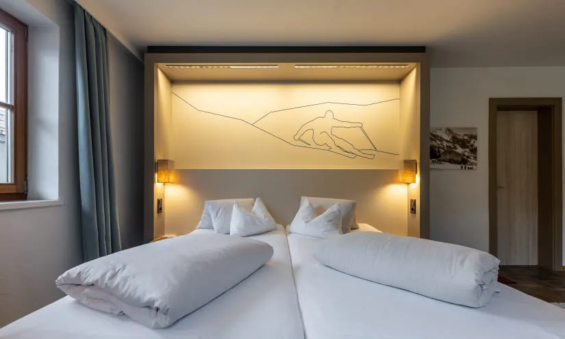 Schlafzimmer mit zwei Betten, stilvolles Lichtdesign und Kunstwerk an der Wand