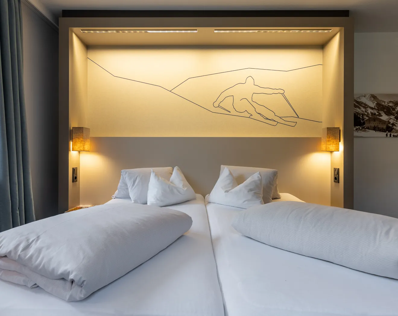 Ein modernes Schlafzimmer mit zwei Betten und stilvollen Beleuchtungselementen.