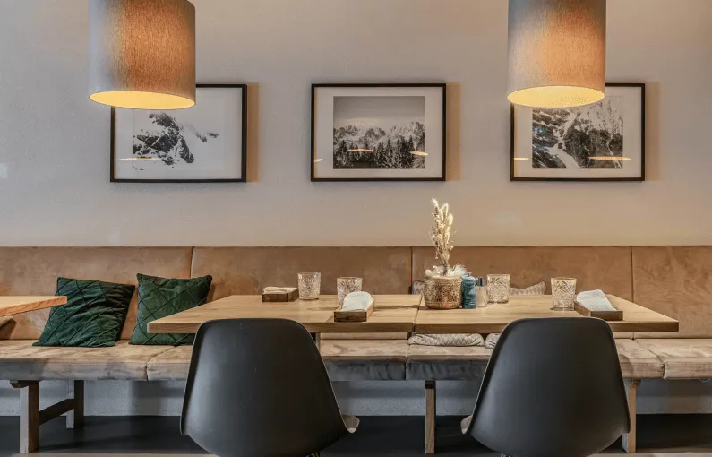 Modernes Restaurant mit Holzinterieur, Bildern an der Wand und beleuchteten Pendelleuchten.