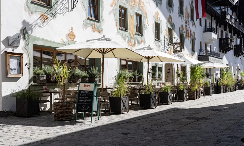 Außensitzbereich mit Sonnenschirmen neben einer Wandmalerei an einem Gebäude