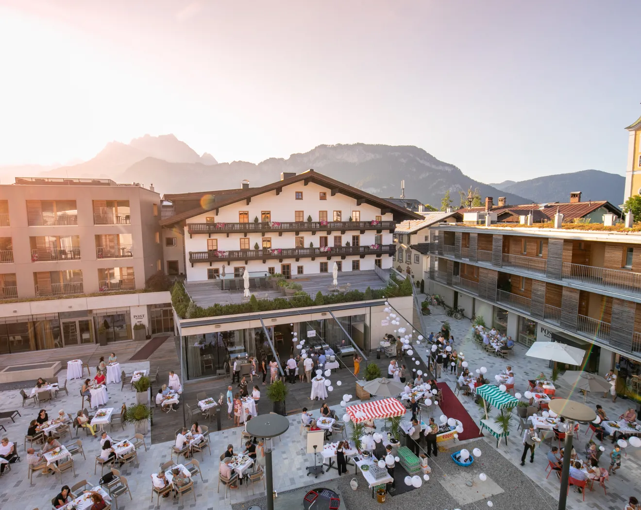 Lebhafte Szenerie eines Sommernachtsfestes mit Gästen und Bergen im Hintergrund