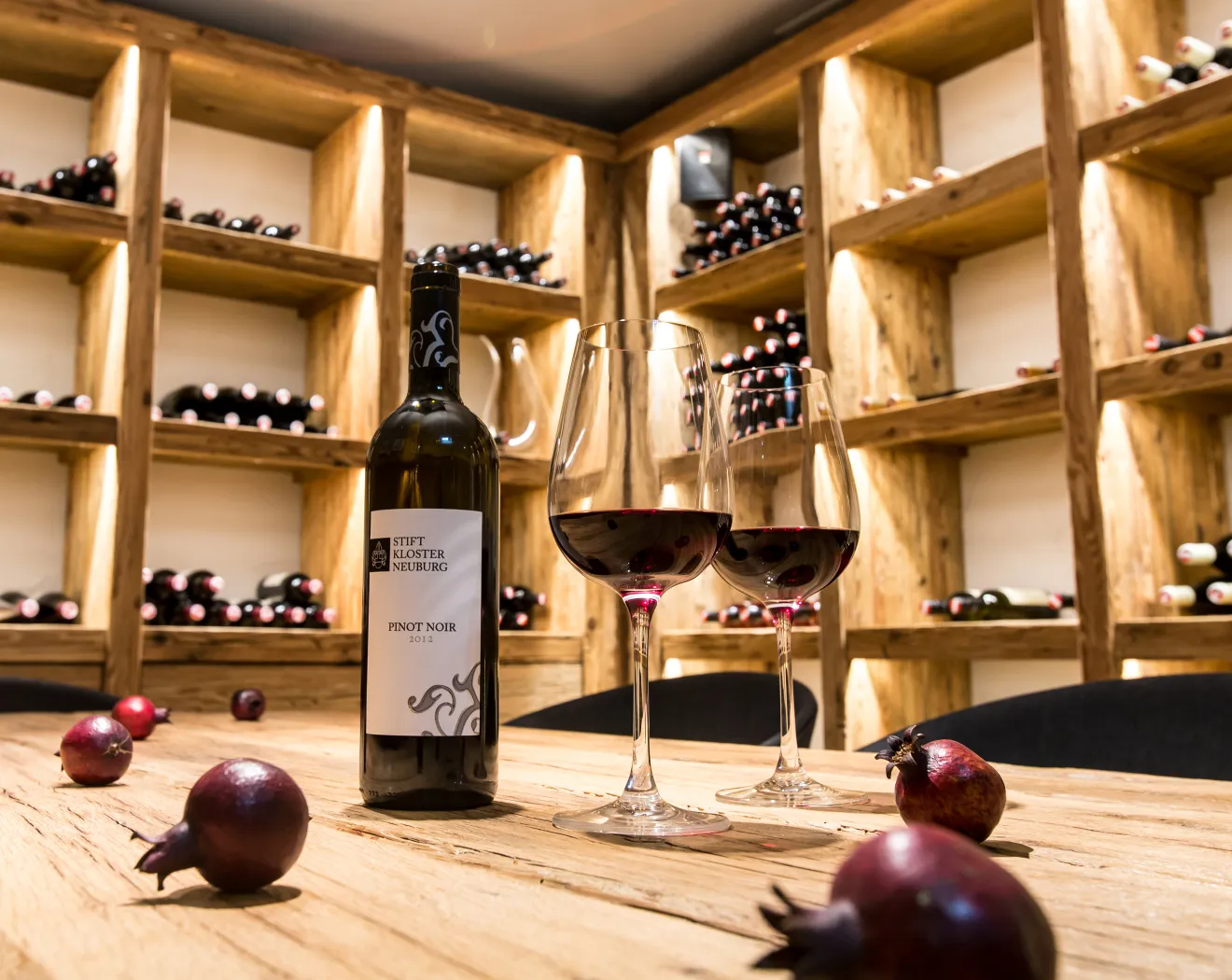 Weinflasche und Gläser in einem Weinkeller mit Holzregalen