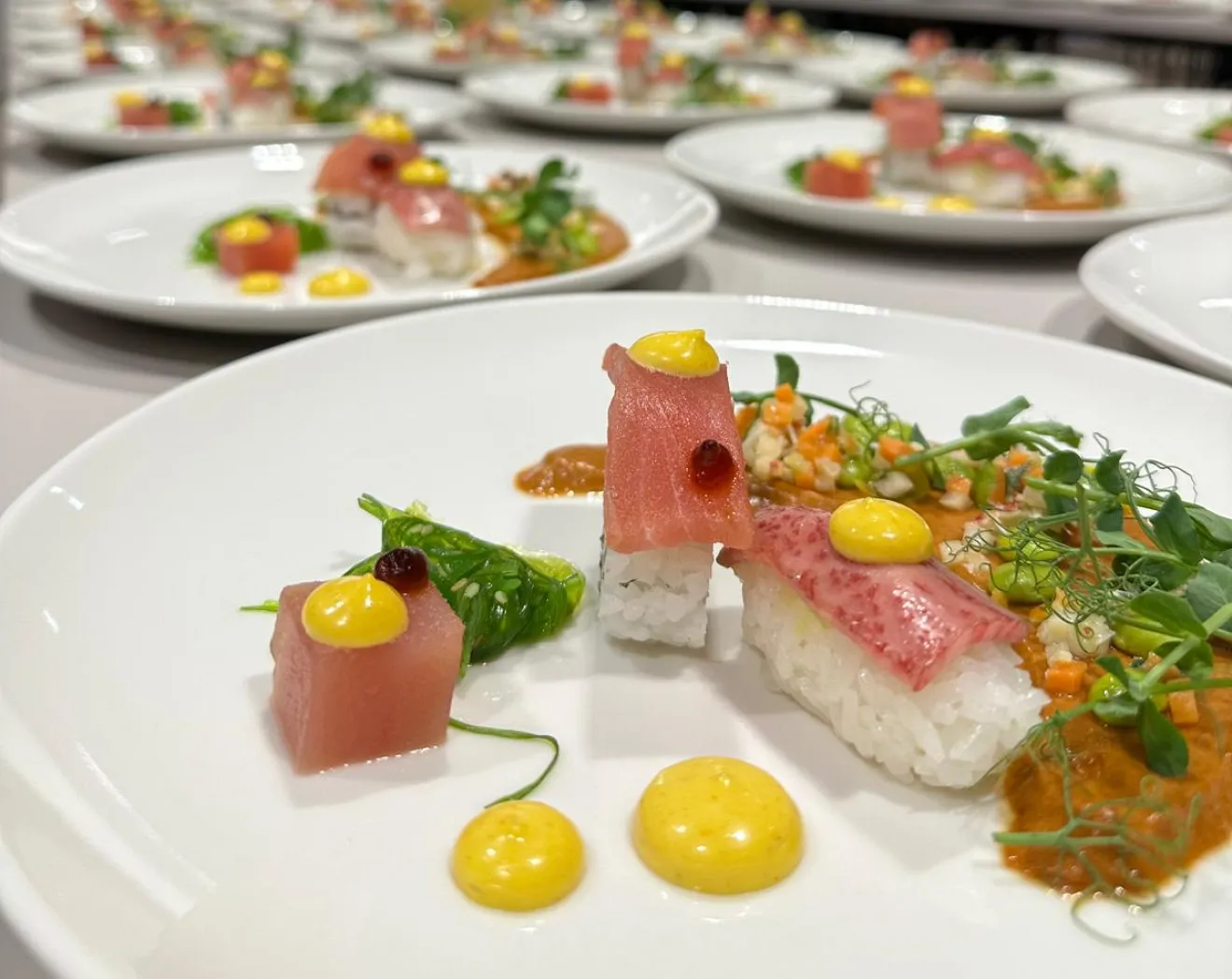 kunstvoll angerichtetes Sushi mit Thunfisch, Garnelen und Sauce auf einem Teller