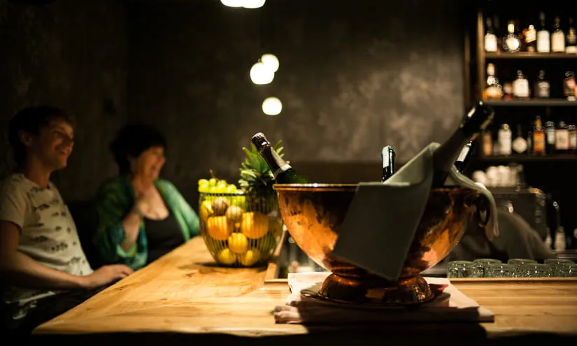 Zwei Personen an einer Bar mit einem großen Kühler und Obstkorb.