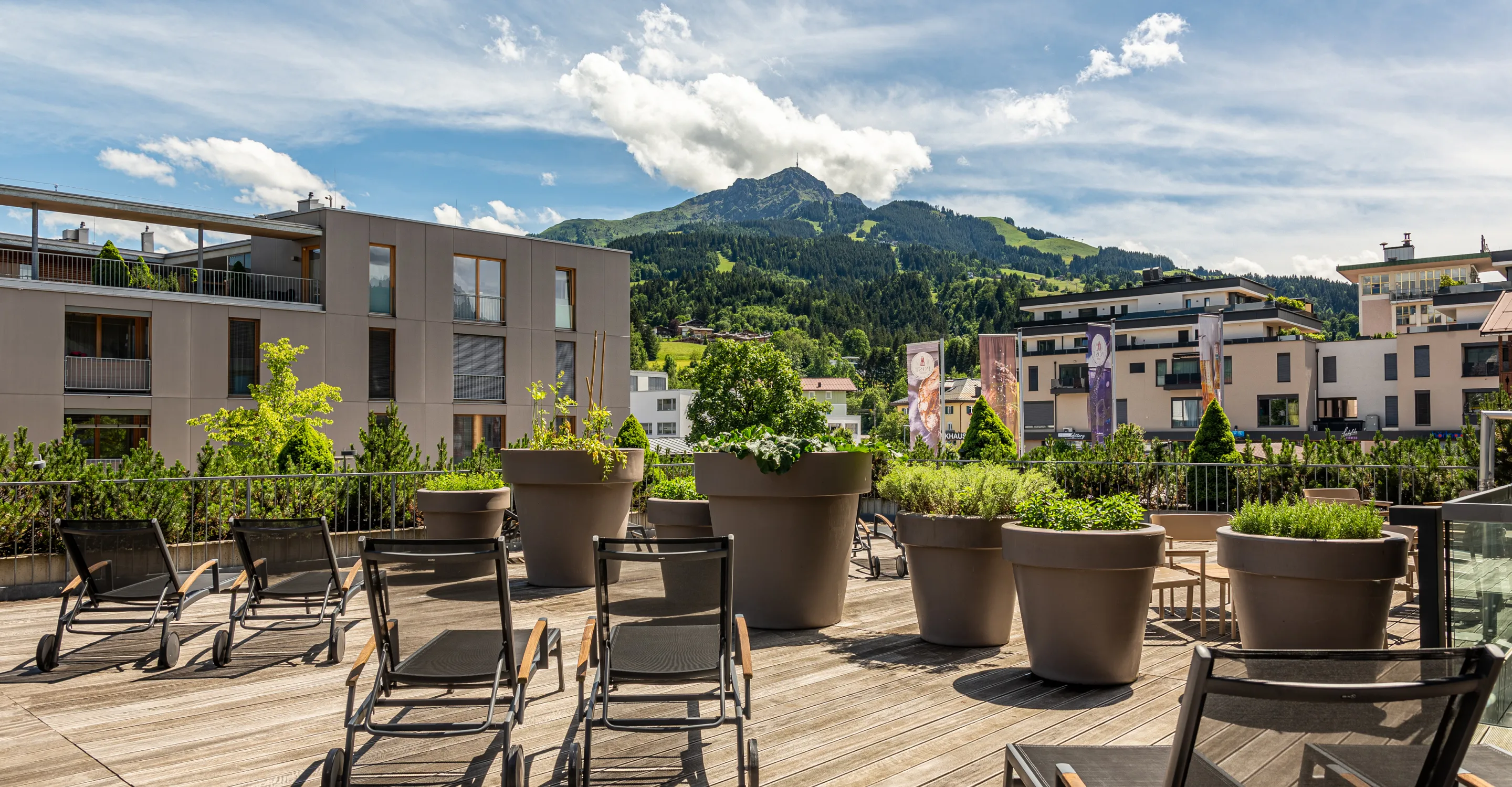 Terrasse mit Liegen und großen Pflanzenkübeln, Bergsicht im Hintergrund.