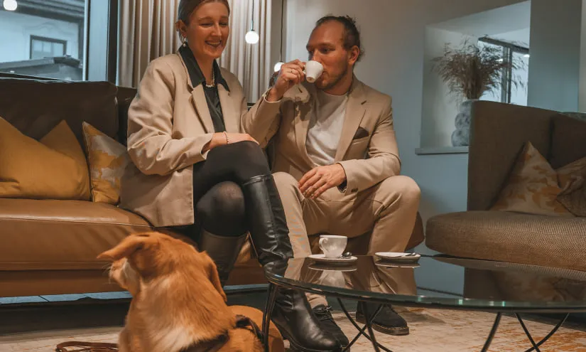 Ein Paar sitzt auf einem Sofa in einem stilvollen Wohnzimmer mit einem Hund auf dem Boden.