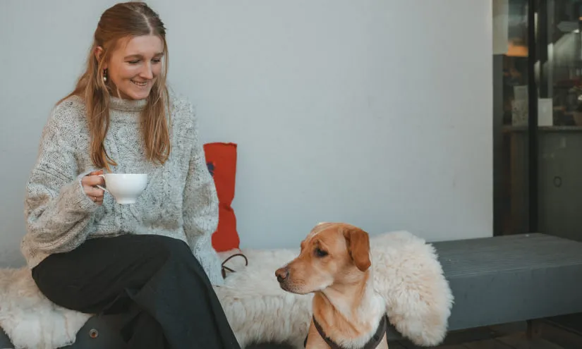 Frau mit Tasse Kaffee und Hund vor POST MARKT