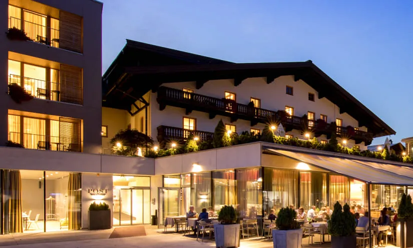 Restaurant mit Außenbereich und alpenländischem Gebäude bei Dämmerung