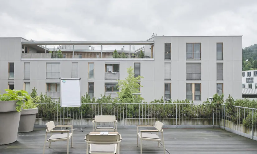 Wettergraue Terrasse mit Stühlen und Pflanzen vor dem Gasthof Post.
