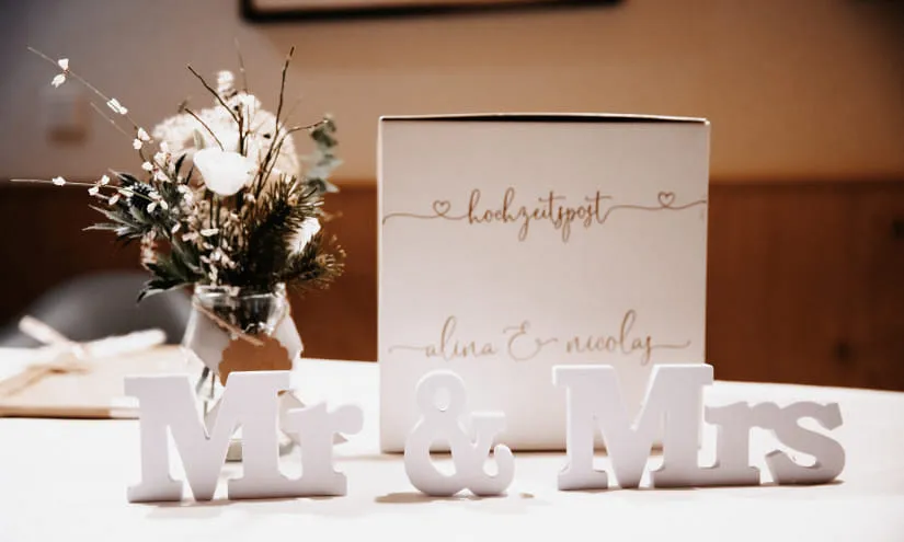 Tischdekoration mit Mr & Mrs und einem Blumengesteck