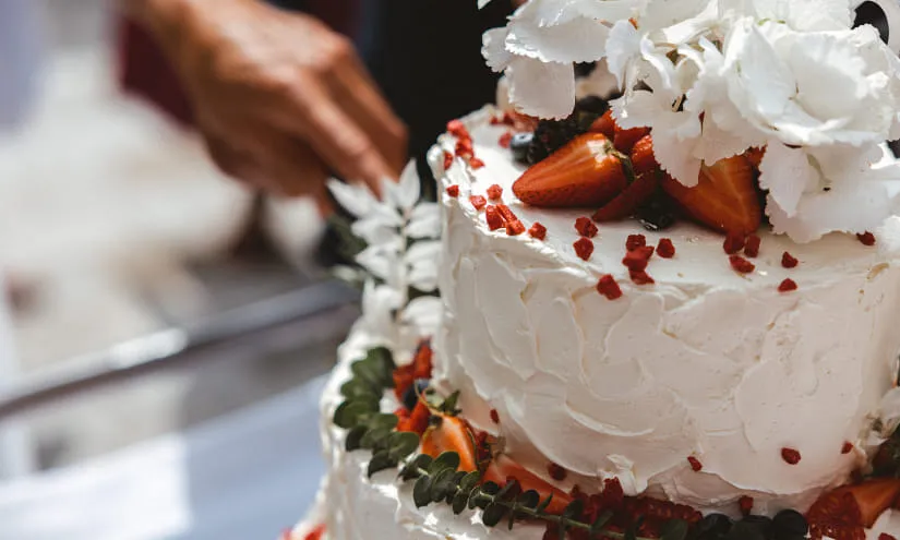 Hochzeitstorte mit Erdbeeren und Orchideen, Person greift nach ihr