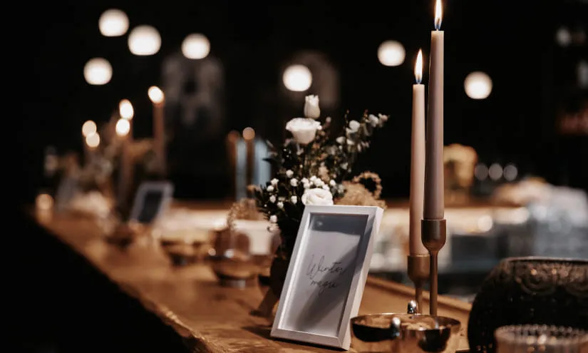 Elegante Tischdekoration mit Kerzen und Blumen in dunkler Umgebung