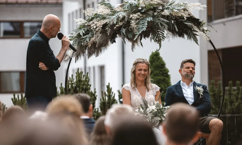 Hochzeitszeremonie unter dekorativem Pflanzenarrangement, Lächeln und Emotionen