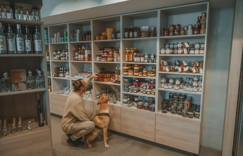 Frau mit Hund in einem Markt, Regal mit verschiedenen Lebensmitteln