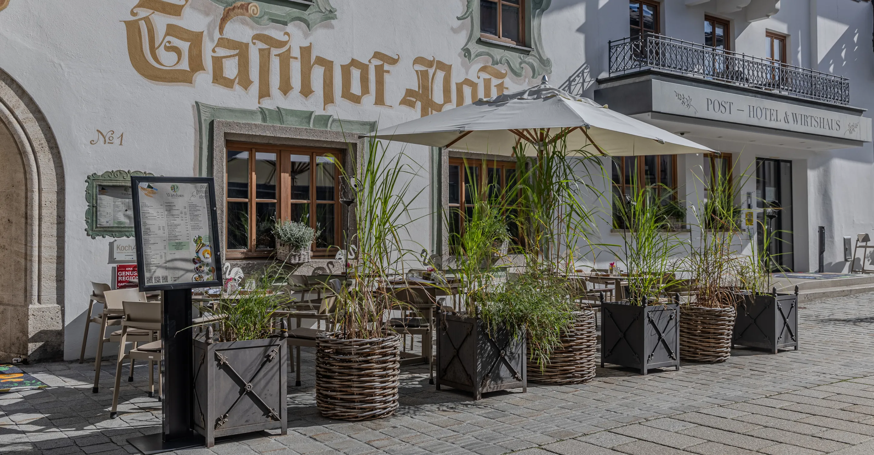 Außenbereich eines Gasthofs mit Pflanzen und Sonnenschirmen